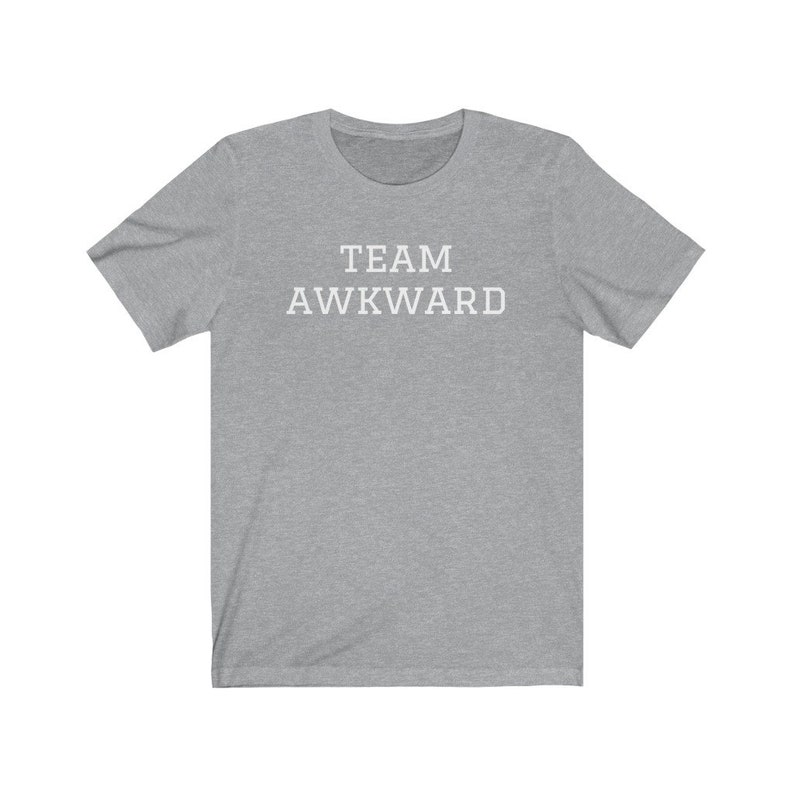 May include: A heather grey t-shirt with the text "TEAM AWKWARD" printed in white on the front.