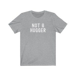 May include: A heather gray t-shirt with the text "NOT A HUGGER" printed in white.