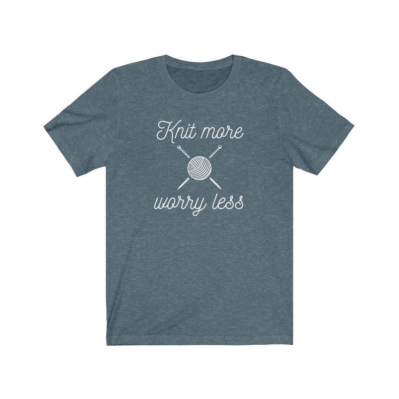 May include: A teal blue t-shirt with the text "Knit more worry less" in white. The text is accompanied by a graphic of a ball of yarn and two knitting needles.
