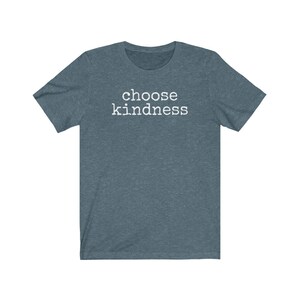 May include: A short-sleeved, heathered teal t-shirt with the words "choose kindness" printed in white block letters across the chest. The shirt has a crew neck and a relaxed fit, suitable for casual wear.