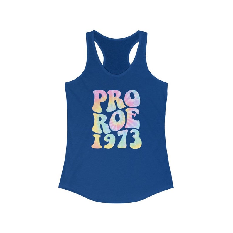 May include: A blue racerback tank top with the words "PRO ROE 1973" in a tie-dye style. The text is in pastel colors, including pink, yellow, and blue. The tank top has a scoop neck and a racerback design.