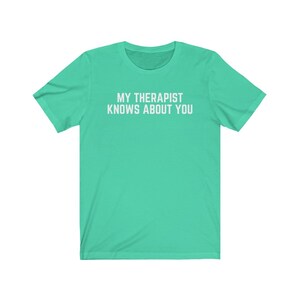 May include: A turquoise t-shirt with the text "My therapist knows about you" printed in white.