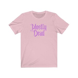 May include: A pink short-sleeved t-shirt with the text "Mostly Dead" in a purple gothic font.