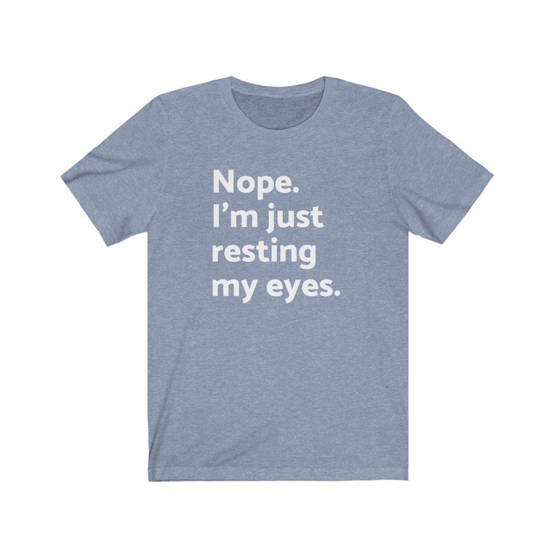 May include: A light blue t-shirt with the text "Nope. I'm just resting my eyes." printed in white.