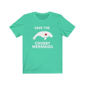 May include: A turquoise blue t-shirt with a white graphic of a manatee with a red heart and the text "Save the Chubby Mermaids".