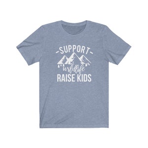 May include: A light blue t-shirt with a white graphic design that says "Support wildlife raise kids" with a mountain range illustration.