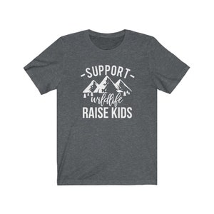 May include: A dark heather grey t-shirt with a white graphic of mountains and trees. The text "Support wildlife raise kids" is printed on the shirt.