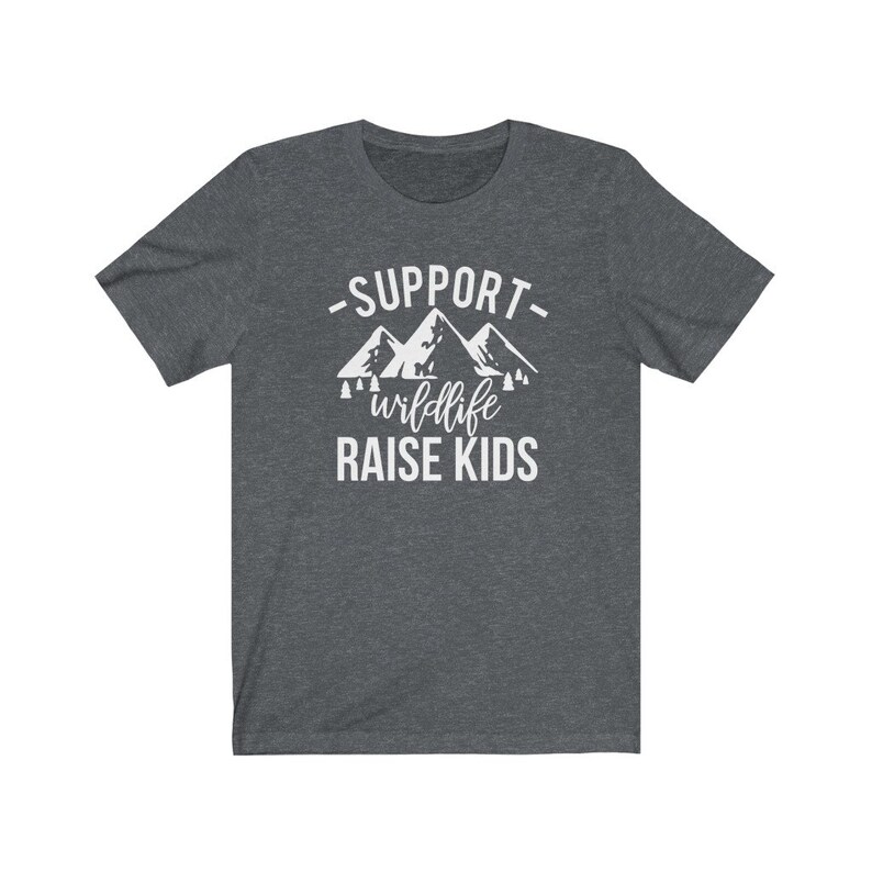 May include: A dark heather grey t-shirt with a white graphic of mountains and trees. The text "Support wildlife raise kids" is printed on the shirt.