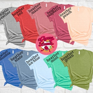 Peut inclure: Une vari&eacute;t&eacute; de t-shirts de diff&eacute;rentes couleurs et chin&eacute;s, y compris chin&eacute; athl&eacute;tique, rouge, mauve, framboise, p&ecirc;che, columbia, ardoise, bleu glacier, menthe et vert. Les t-shirts sont dispos&eacute;s en cercle autour d'un graphique rose et rouge qui dit "Cherry Bomb".