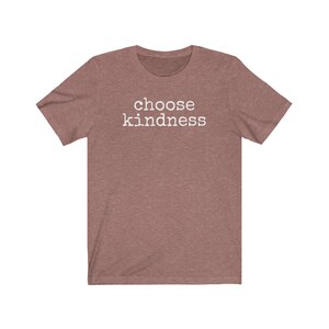 May include: A short-sleeved, heathered mauve t-shirt with the words "choose kindness" printed in white block letters across the chest. The shirt has a crew neck and a casual fit, suitable for everyday wear.
