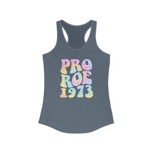 May include: A slate blue racerback tank top with the words "PRO ROE 1973" in a tie-dye design. The text is in a retro font with pastel colors of pink, yellow, and blue.