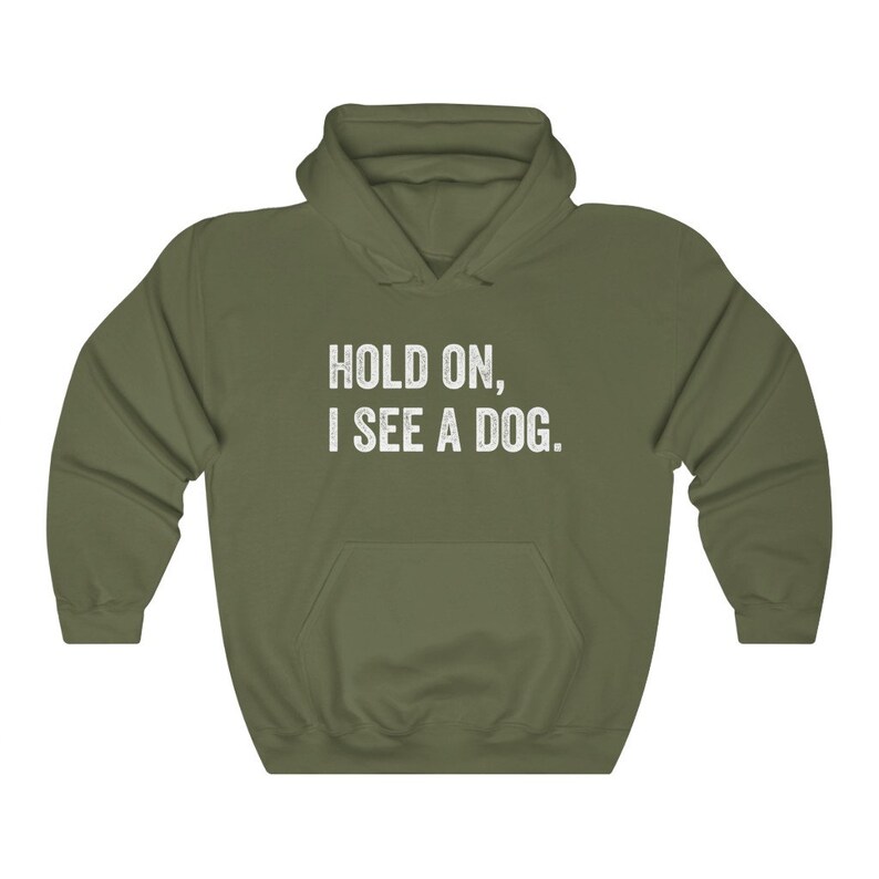 Pode incluir: Uma camisa de frio com capuz verde com o texto "HOLD ON, I SEE A DOG." impresso em branco na frente.