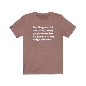 Puede incluir: Una camiseta marr&oacute;n jaspeada con texto blanco que dice "Mr. Rogers no me prepar&oacute; adecuadamente para la gente de mi vecindario."