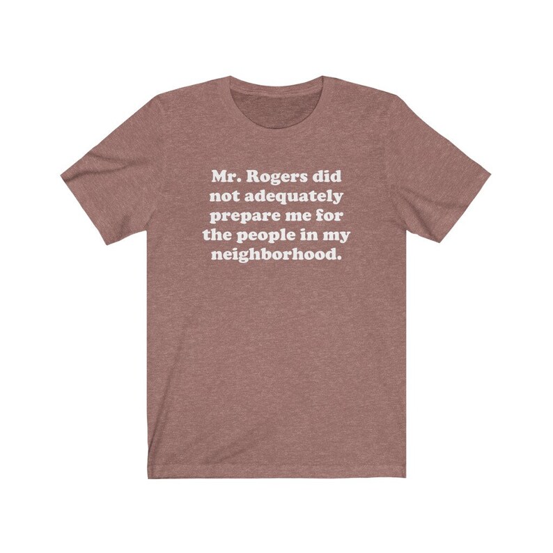 Puede incluir: Una camiseta marr&oacute;n jaspeada con texto blanco que dice "Mr. Rogers no me prepar&oacute; adecuadamente para la gente de mi vecindario."
