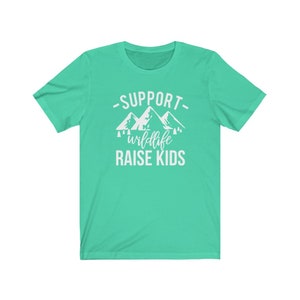 May include: A turquoise t-shirt with a white graphic design that says "Support Wildlife Raise Kids" with a mountain range and trees.