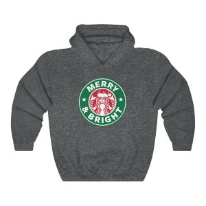 May include: A dark gray hooded sweatshirt with a green and white logo that says "Merry & Bright" with a stylized image of a woman wearing a Santa hat.