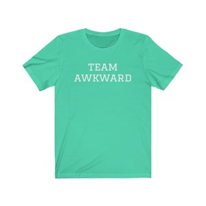 May include: A turquoise t-shirt with the text "TEAM AWKWARD" printed in white.