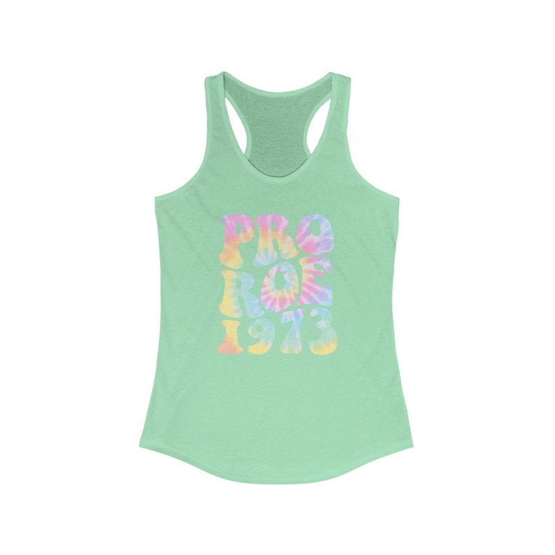 May include: A light green racerback tank top with the words "PRO ROE 1973" in a tie-dye design. The text is in shades of pink, yellow, and blue. The tank top has a scoop neck and a racerback design.