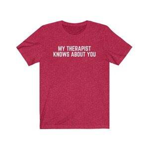 May include: Red heather t-shirt with white text that reads "My therapist knows about you."