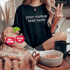 May include: Black t-shirt with the text "your custom text here!" in white. The image also includes a bowl of cereal, a black mug, and a copper tray. Two cherry graphics with text are also visible.