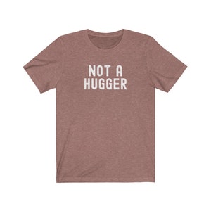 May include: A heather gray t-shirt with the text "NOT A HUGGER" printed in white.