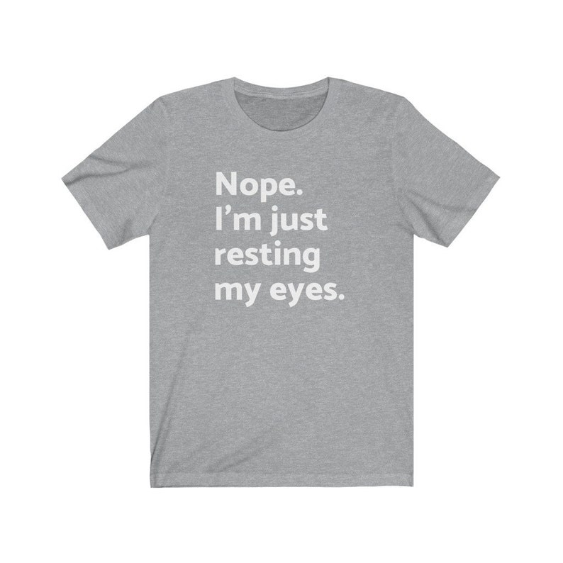May include: A heather grey t-shirt with the text "Nope. I'm just resting my eyes." printed in white.