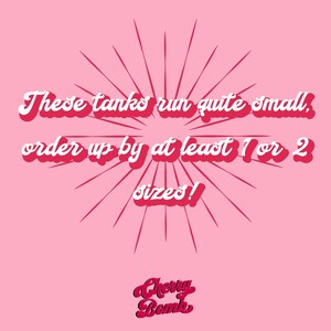 May include: Pink background with red radial lines emanating from the center. Text in white with a red outline reads, "These tanks run quite small, order up by at least 1 or 2 sizes!" The Cherry Bomb logo is at the bottom.