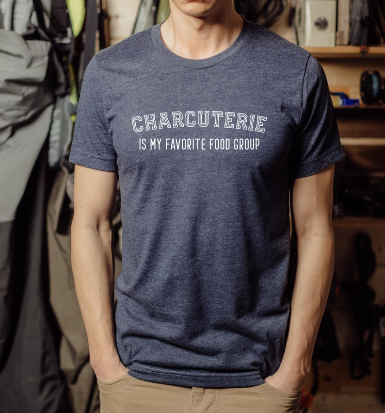 Peut inclure: Un t-shirt bleu fonc&eacute; avec le texte "CHARCUTERIE IS MY FAVORITE FOOD GROUP" en blanc.