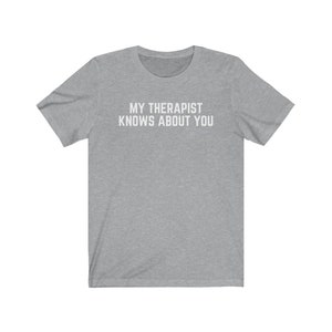 May include: A heather grey t-shirt with the text "MY THERAPIST KNOWS ABOUT YOU" printed in white.