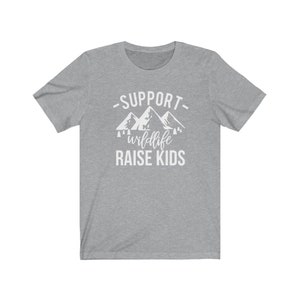 May include: Gray t-shirt with white text that reads "Support wildlife raise kids" with a graphic of mountains and trees.