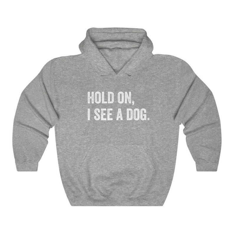 Pode incluir: Camisola de moletom cinza com capuz com o texto "HOLD ON, I SEE A DOG." impresso em branco.