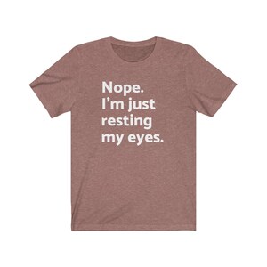 May include: A heather brown t-shirt with the text "Nope. I'm just resting my eyes." printed in white.