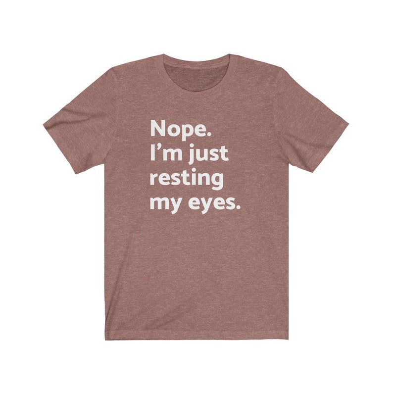 May include: A heather brown t-shirt with the text "Nope. I'm just resting my eyes." printed in white.