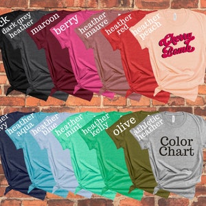 May include: Color chart of t-shirts in various colors, including black, dark grey heather, maroon, berry, heather mauve, heather red, heather peach, heather navy, heather aqua, heather blue, heather mint, heather kelly, olive, athletic heather, and grey. The t-shirt in the center has the text "Cherry Bomb" in red and white.