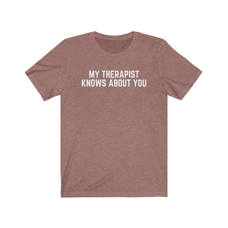 May include: A heather brown t-shirt with the text "MY THERAPIST KNOWS ABOUT YOU" printed in white.
