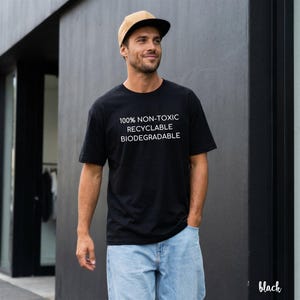 May include: Black t-shirt with white text: "100% NON-TOXIC RECYCLABLE BIODEGRADABLE." The person is wearing a tan and black baseball cap and light blue jeans. The word "black" is in the bottom right corner.