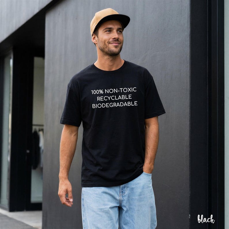 May include: Black t-shirt with white text: "100% NON-TOXIC RECYCLABLE BIODEGRADABLE." The person is wearing a tan and black baseball cap and light blue jeans. The word "black" is in the bottom right corner.