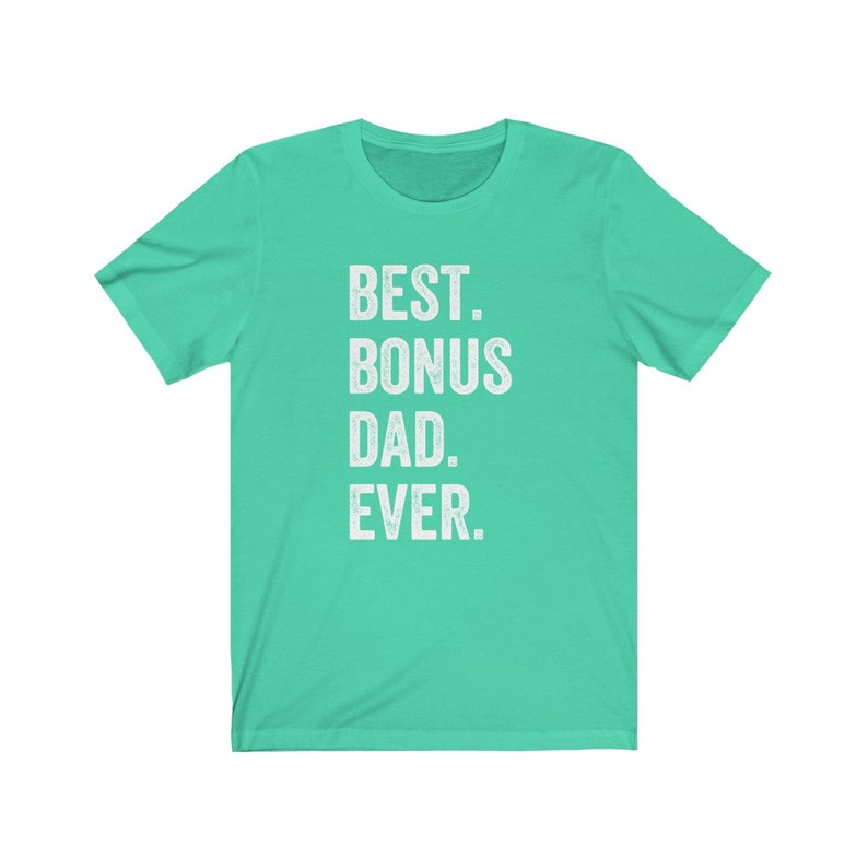 Puede incluir: Una camiseta de color turquesa con el texto "BEST. BONUS DAD. EVER." impreso en blanco. La camiseta tiene mangas cortas y cuello redondo. El texto est&aacute; centrado en la parte delantera de la camiseta.