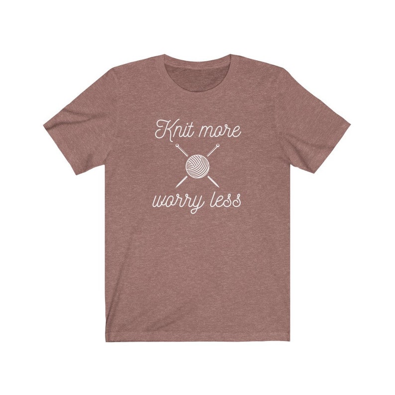 May include: A heather brown t-shirt with the text "Knit more worry less" in white. The text is accompanied by a graphic of a ball of yarn and two knitting needles.
