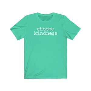 May include: A short-sleeved, teal t-shirt with the words "choose kindness" printed in white block letters across the chest. The shirt has a crew neck and is made of a soft material.