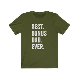 Puede incluir: Camiseta verde oliva con el texto blanco "BEST. BONUS DAD. EVER." La camiseta tiene mangas cortas y cuello redondo. El texto est&aacute; en negrita y sin serifa.