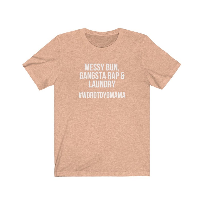 K&ouml;nnte beinhalten: Ein pfirsichfarbenes T-Shirt mit dem wei&szlig;en Text "MESSY BUN, GANGSTA RAP & LAUNDRY" und dem Hashtag "#WORDTOYOMAMA". Das T-Shirt hat kurze &Auml;rmel und einen Rundhalsausschnitt.