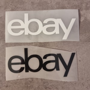 Könnte beinhalten: Zwei eBay-Logos, eines weiß und eines schwarz, auf einem transparenten Hintergrund.