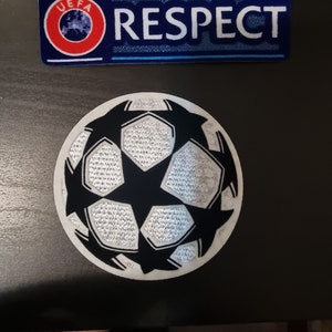 May include: A white and black soccer ball patch with a star in the center. The patch has the UEFA logo and the word "RESPECT" on a blue and white background.