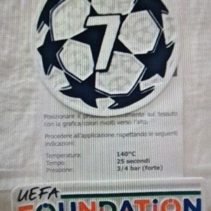 Può includere: Un pallone da calcio bianco e blu con il numero 7 al centro. Il pallone è circondato da un contorno nero e stelle. Il testo "UEFA FOUNDATION for children" è sotto il pallone. Il testo "Passa il mouse per ingrandire" è sotto il testo.