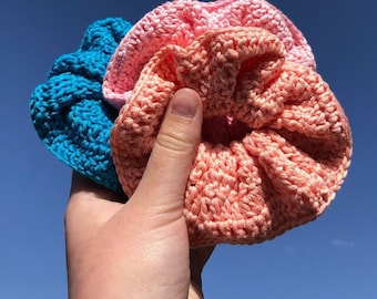 May include: Three crocheted hair scrunchies in pink, light pink, and teal.