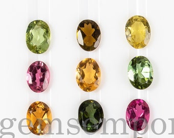 May include: A collection of 18 oval-shaped gemstones in various colors, including green, pink, orange, and brown. The gemstones are arranged in three rows of six, on a white background. The text "Thegemsemporium" is visible in the center of the image.
