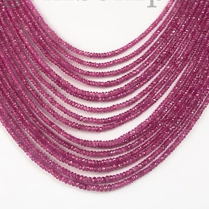 Puede incluir: Un collar de múltiples hilos compuesto por numerosas cuentas pequeñas de color rosa intenso. El collar está colocado sobre un maniquí blanco, mostrando su diseño en capas. Las cuentas parecen ser de tamaño y forma uniformes, creando una apariencia rica y texturizada. El texto "emsemp" es parcialmente visible.