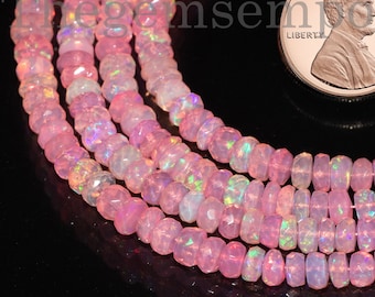 May include: A strand of pink opal beads with iridescent shimmer. The beads are faceted and have a slightly irregular shape. A US penny is included for scale.