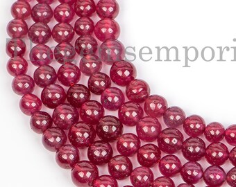 May include: A strand of deep red ruby beads, each bead is round and smooth. The beads are arranged in a circular pattern, creating a beautiful and elegant display.